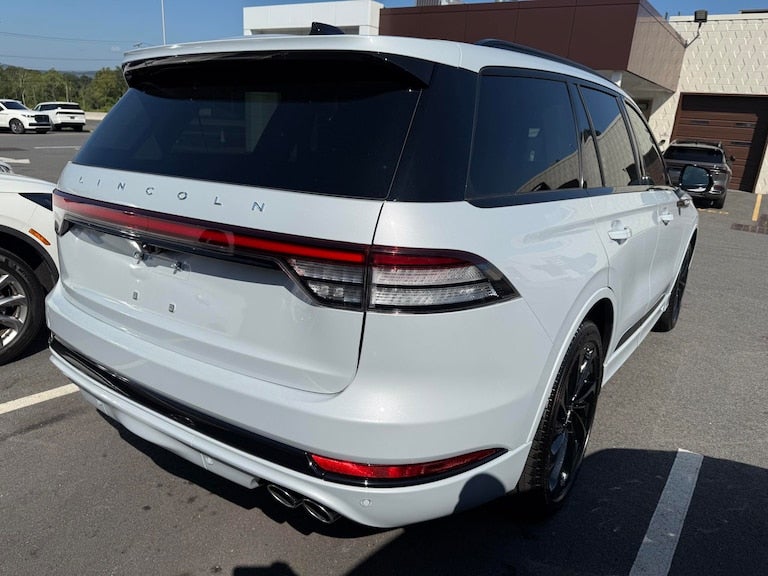 Rear view of a white Lincoln Aviator SUV with tinted windows, parked outdoors on asphalt.