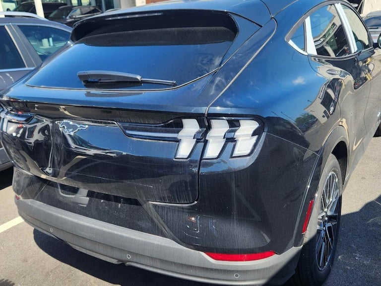 Rear view of a black Ford Mustang Mach-E with damage to the back hatch and bumper.