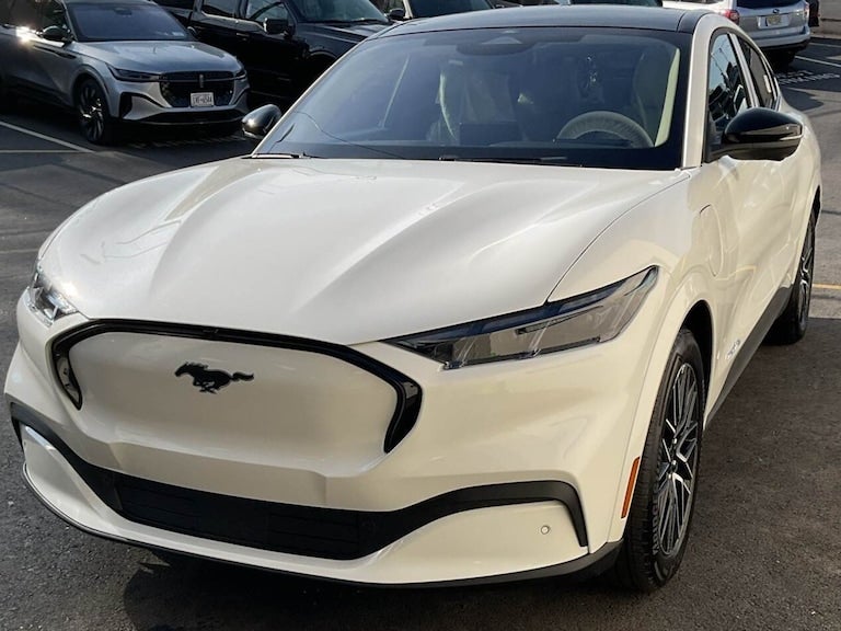 Front view of a white Ford Mustang Mach-E electric SUV, parked outdoors.